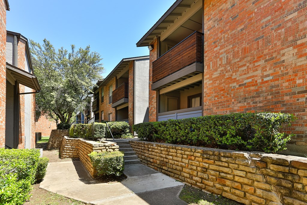 A row of houses with a brick wall in front.