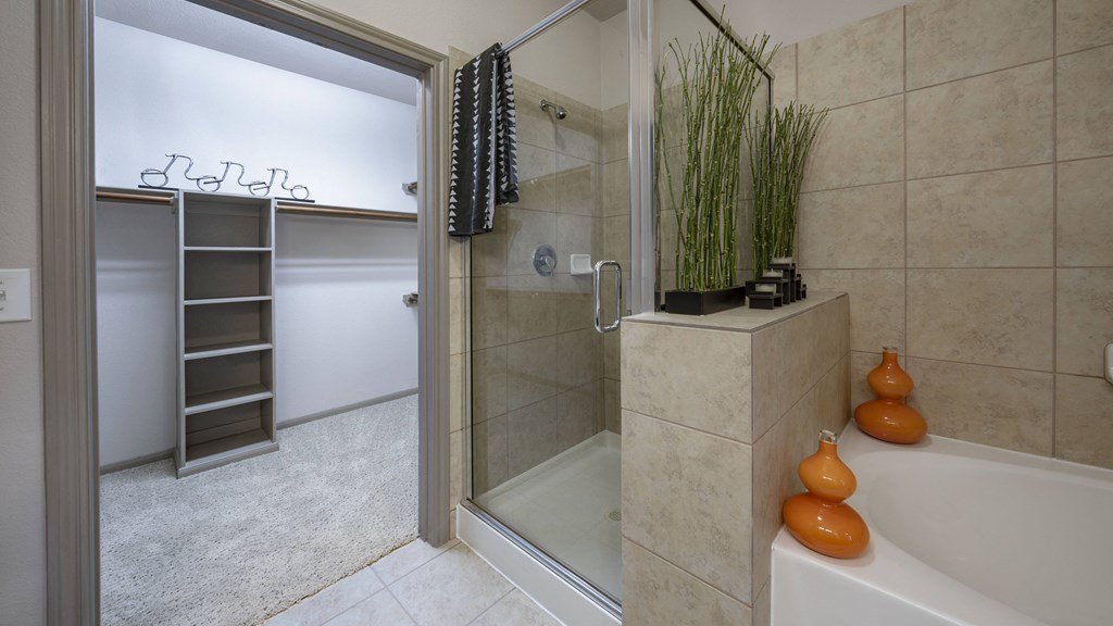 a bathroom with a shower and a tub and a plant