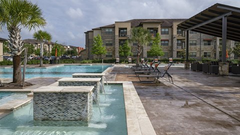 a swimming pool with chairs and a building in the background