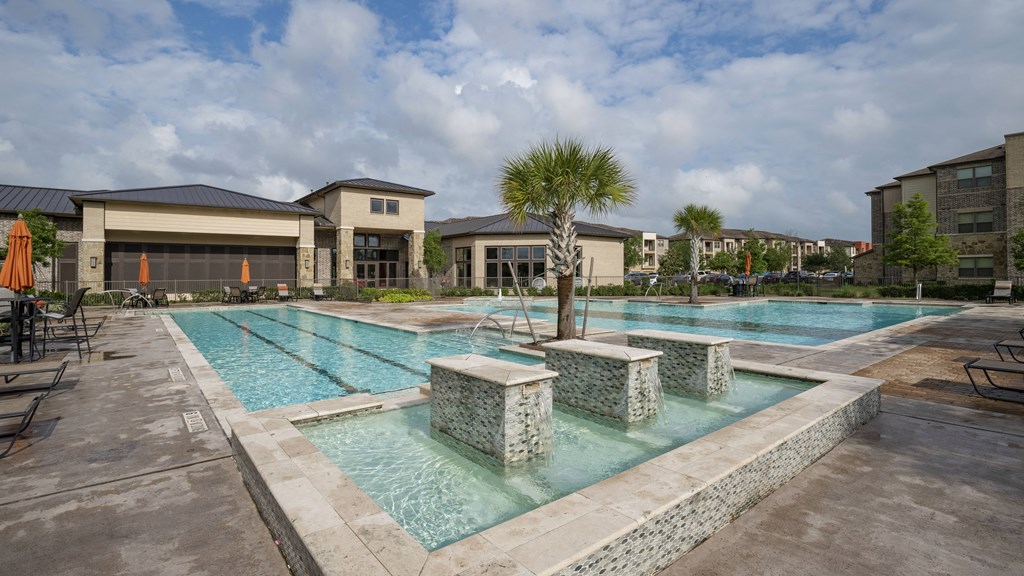 a large swimming pool with palm trees and buildings in the background