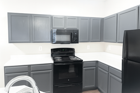 A black oven and microwave in a kitchen with grey cabinets.