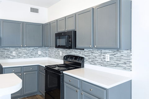 A kitchen with a black microwave above the stove.