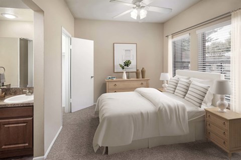 Bedroom with large windows, ceiling fan, and ensuite vanity area.