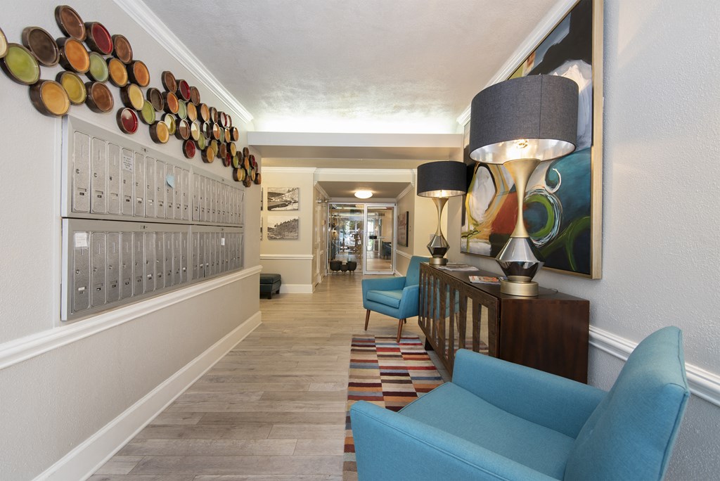 a hallway with blue couches and chairs and a large painting on the wall