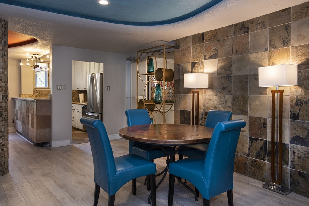 a dining area with a table and chairs and a kitchen in the background