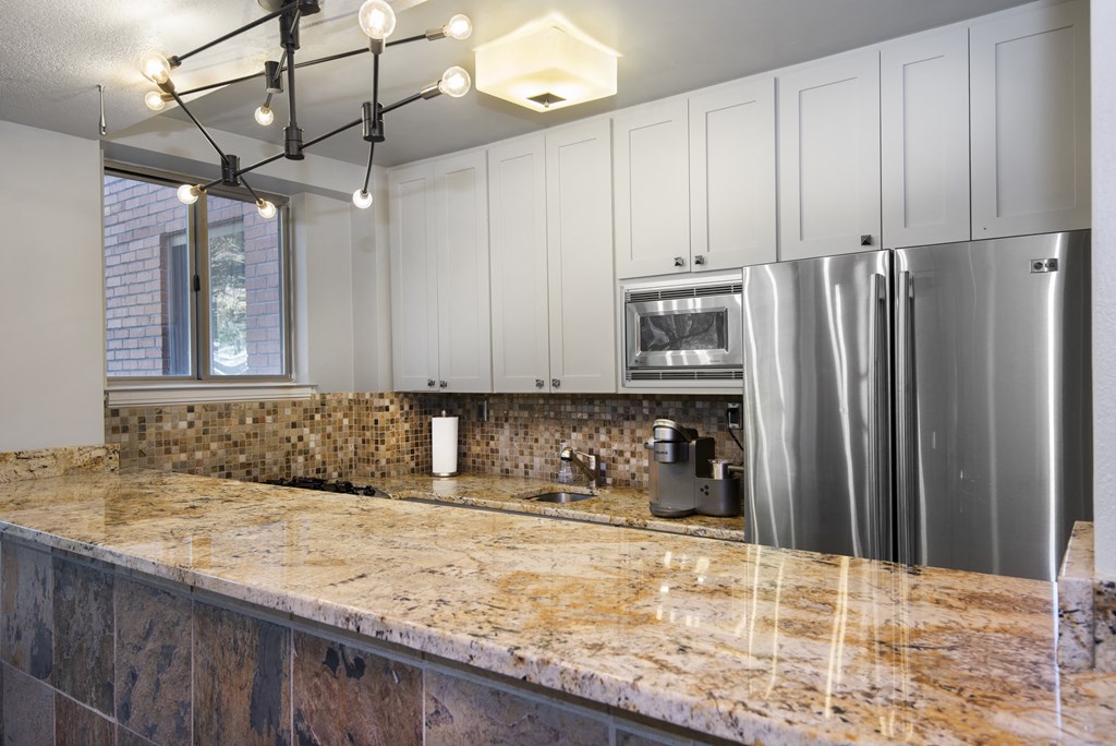 a kitchen with white cabinets and a granite counter top