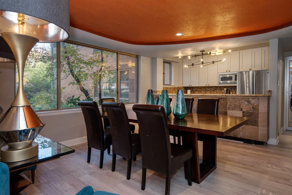 a dining room with an orange ceiling and a long wooden table with black chairs