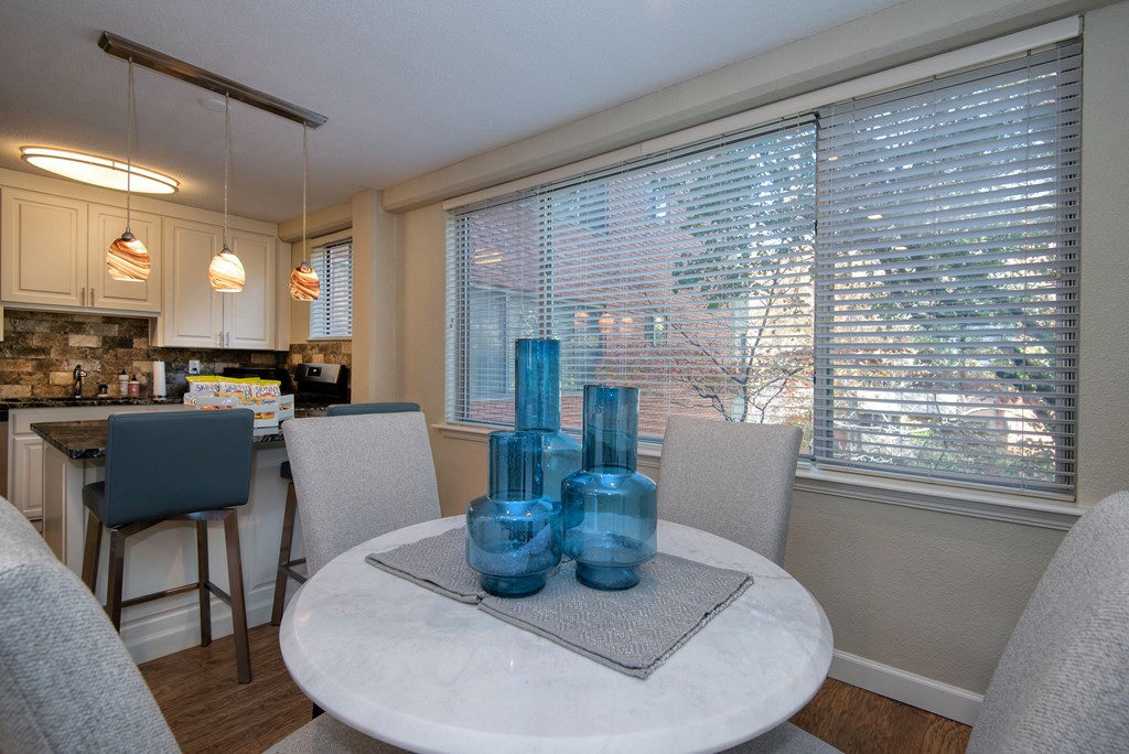a dining room with a table and chairs and a kitchen in the background
