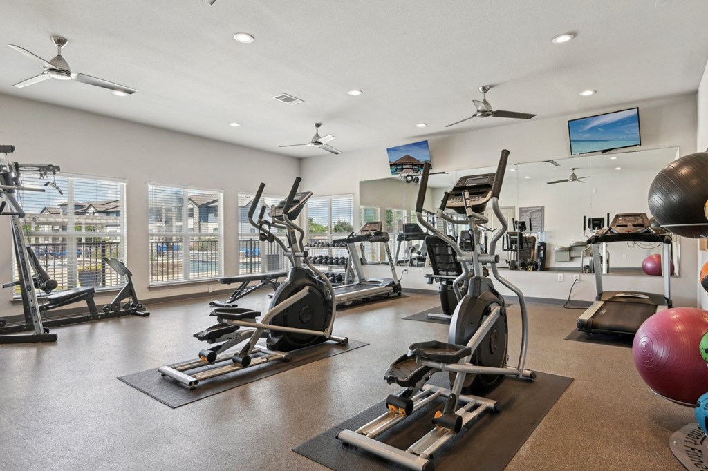a gym with treadmills and other exercise equipment and windows