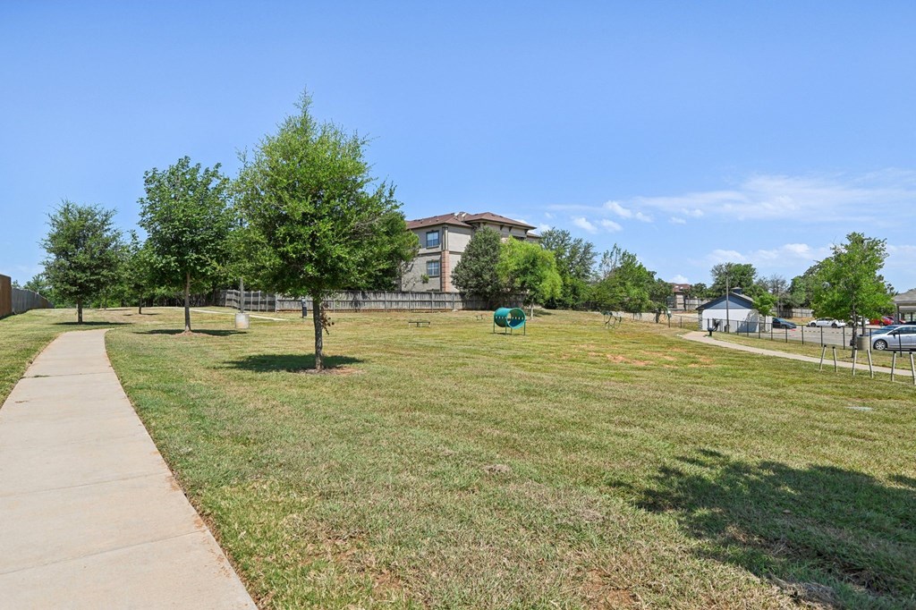 a park with grass and trees in front of a building