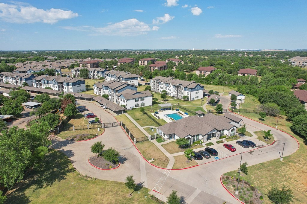 an aerial view of an apartment complex with cars parked in a parking lot