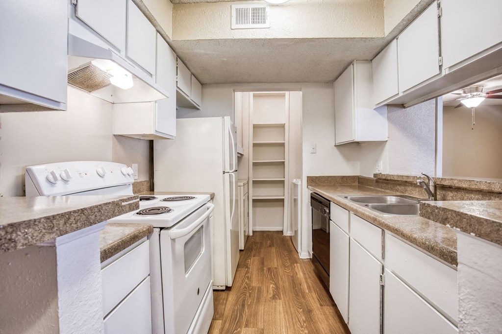 a kitchen with white cabinets and white appliances and wood flooring