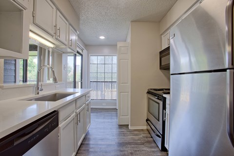 A kitchen with white cabinets and a stainless steel refrigerator.