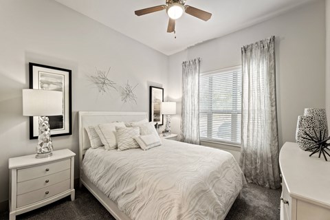 A bedroom with a bed, nightstand, and a ceiling fan.