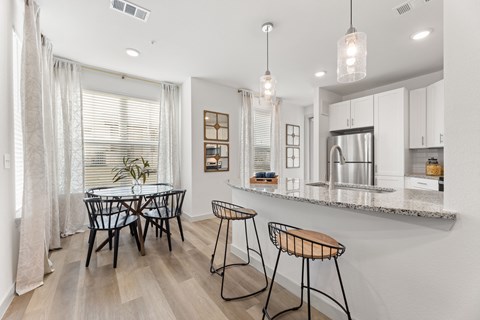 a kitchen with a bar and a dining area with a table and chairs