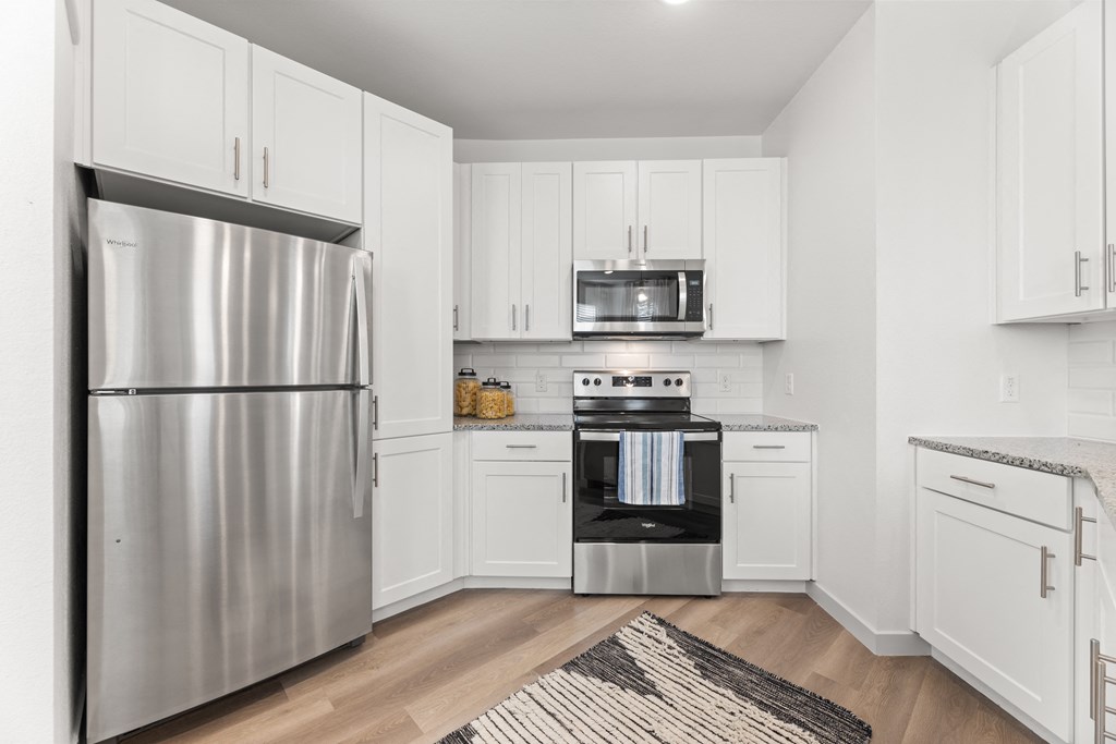a white kitchen with stainless steel appliances and white cabinets