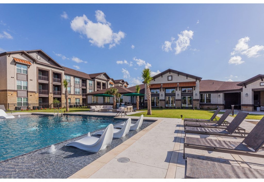 a swimming pool with lounge chairs in front of an apartment building