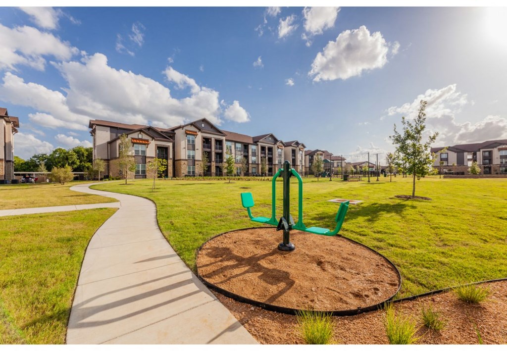 a park with a playground and apartments in the background