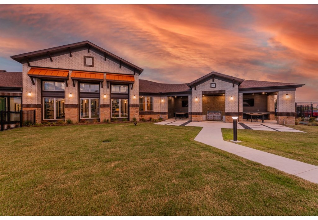 a large house with a yard and a sunset sky