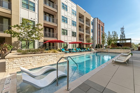 A swimming pool with lounge chairs and umbrellas.
