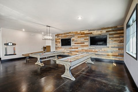 a game room with two pool tables and two televisions