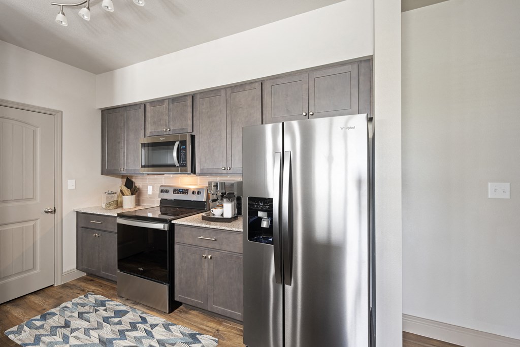a kitchen with gray cabinets and stainless steel appliances
