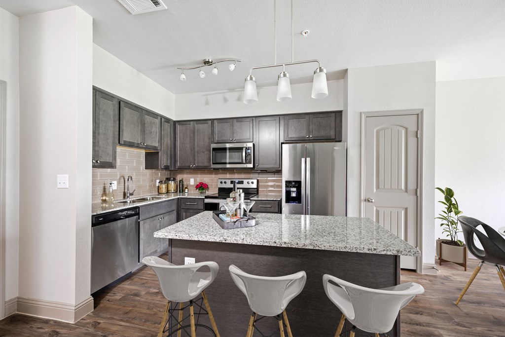 a kitchen with a large island with four chairs around it