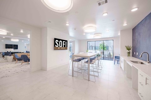 A modern kitchen with a dining area and a sign that says "SOFI" on the wall.