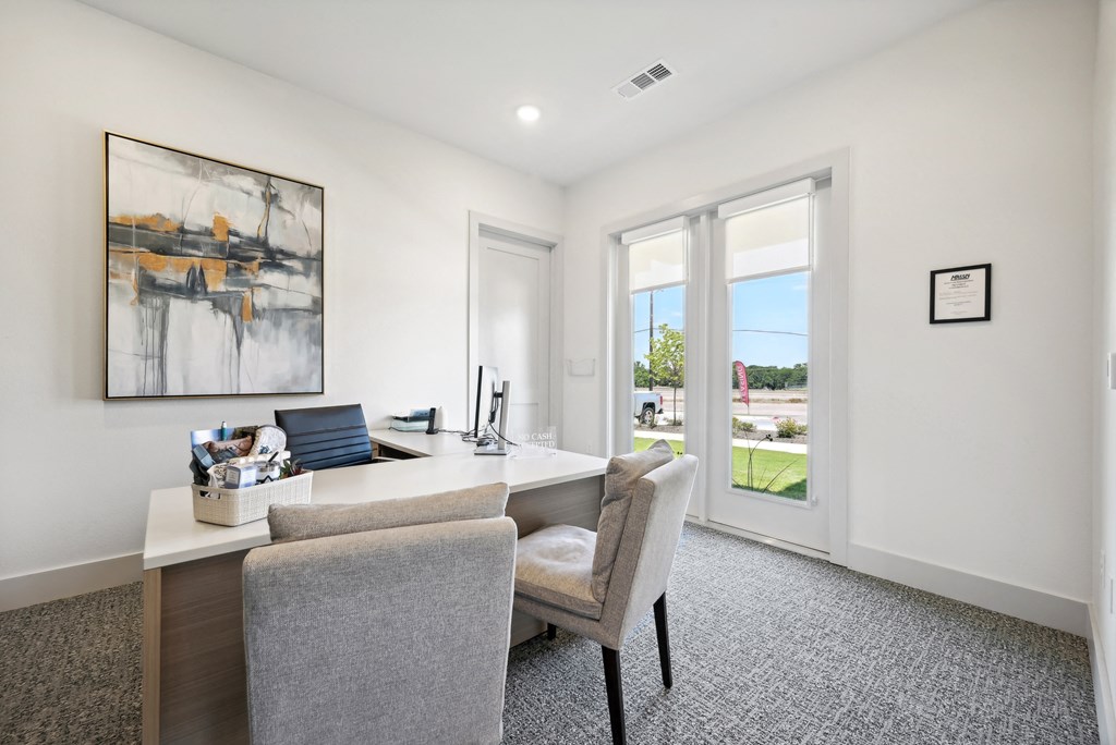 a home office with a desk and chairs and a window