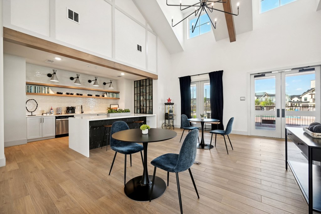 a living room with a kitchen and a dining area with chairs and a table