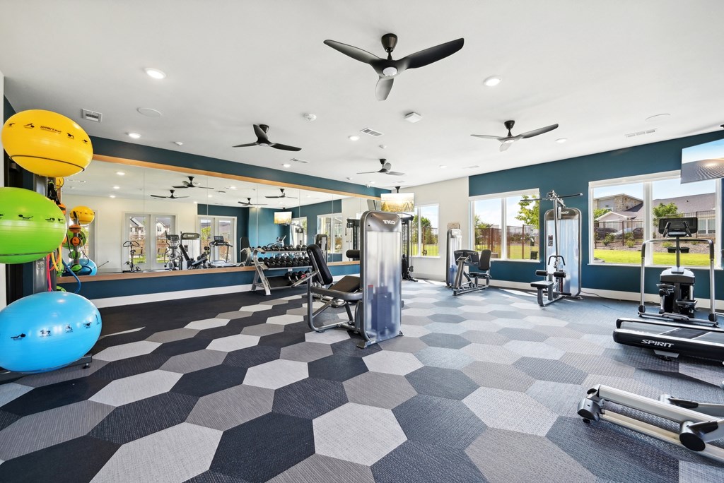 a gym with weights and cardio machines and a large window