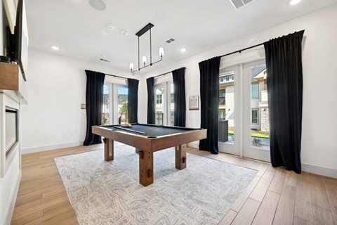 a game room with a pool table and windows with black curtains