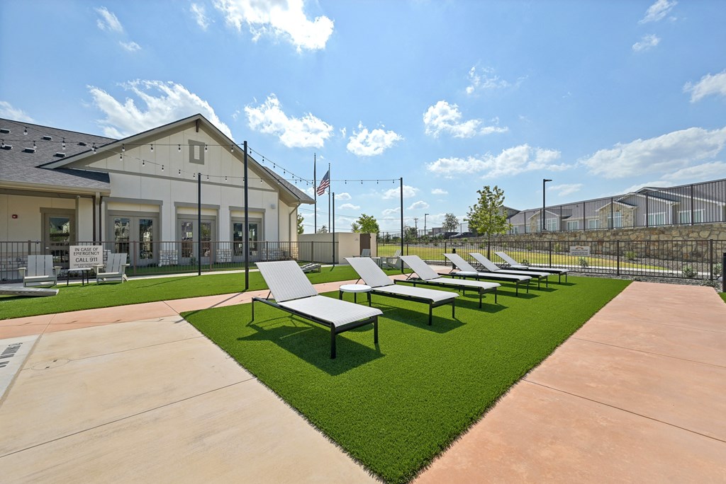 a row of lounge chairs on the grass outside of a building