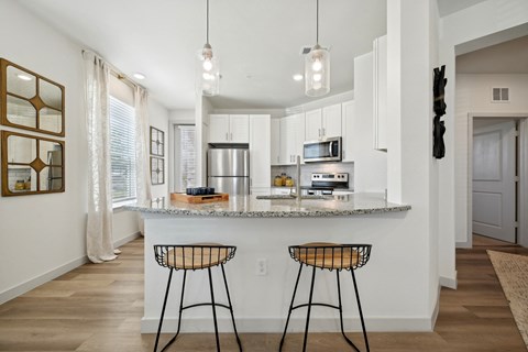 an open kitchen with bar stools in front of a granite counter top