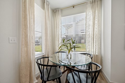 a dining room with a glass table and three chairs in front of a window