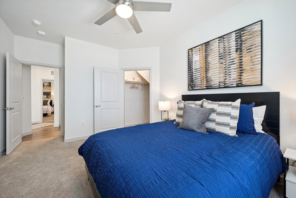 a bedroom with a blue bed and a ceiling fan