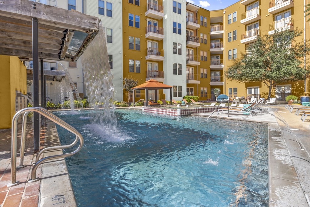 a swimming pool with a waterfall in front of an apartment building