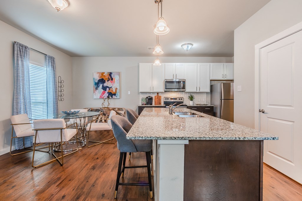 a kitchen with an island and a dining room with a table and chairs