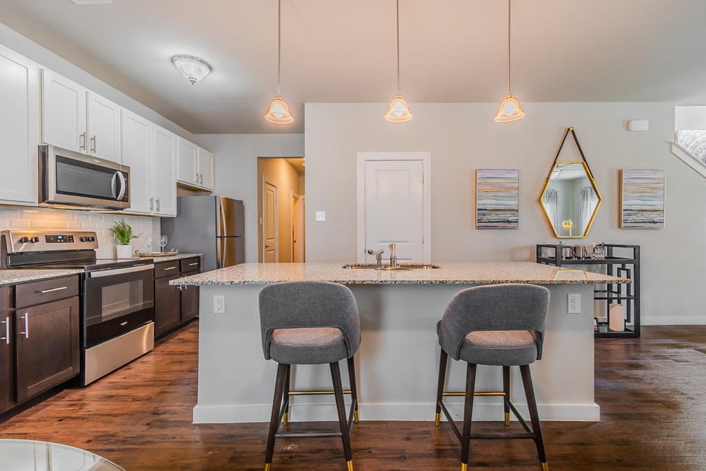 an open kitchen with a marble counter top and two stools
