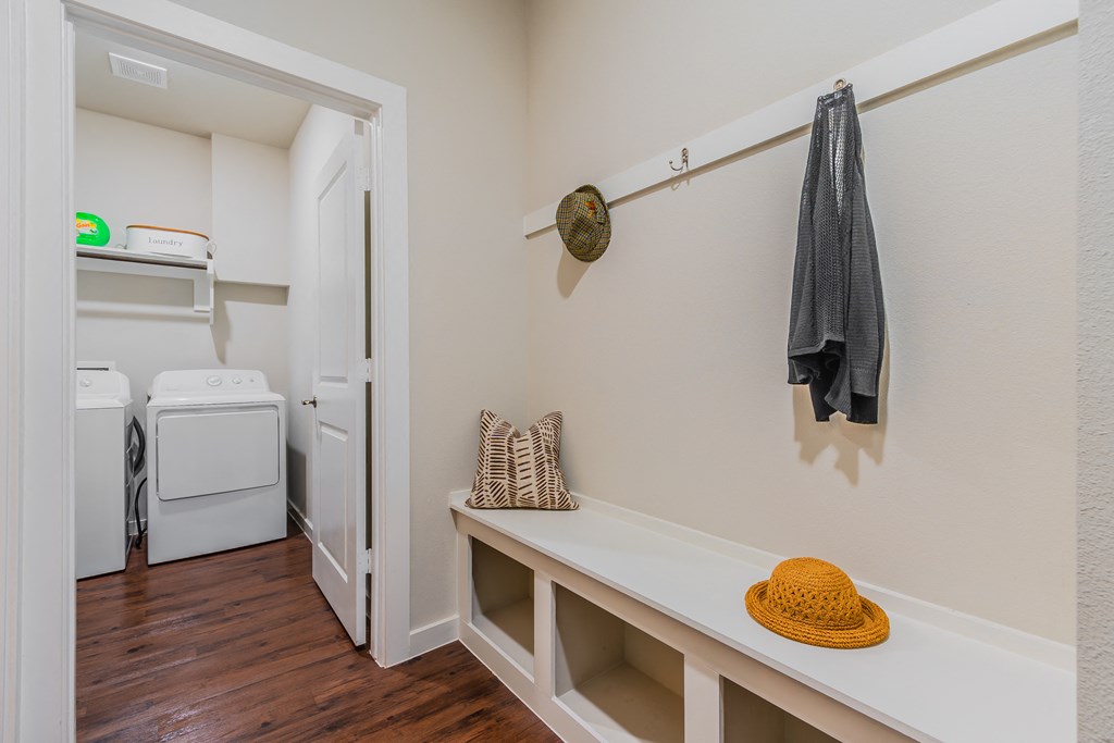a laundry room with a washer and dryer and a shelf with a hat
