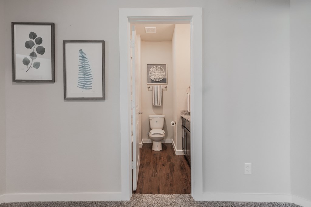 a bathroom with a toilet and a sink and a hallway with a door to it
