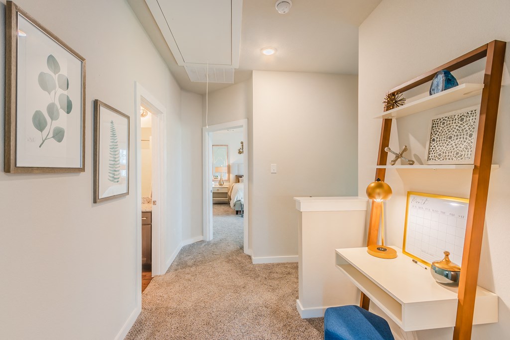 a home office with a desk and a mirror and a hallway to a bedroom