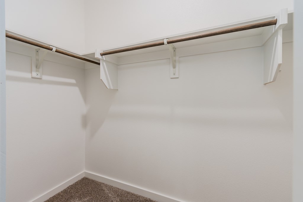 a walk in closet in a bedroom with white walls and