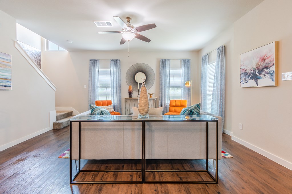 a living room with a table and a ceiling fan