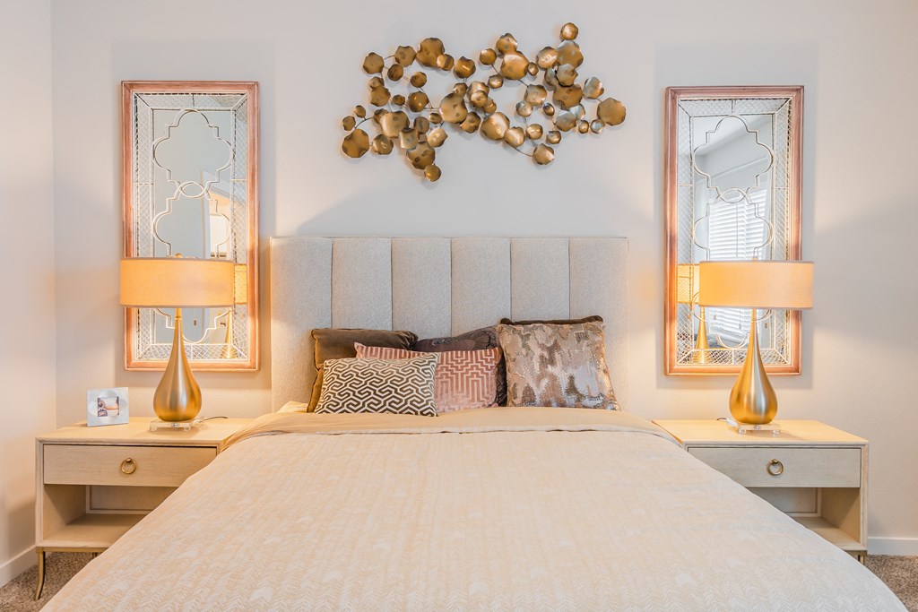 a bedroom with a bed and two lamps and a wall with a flower arrangement