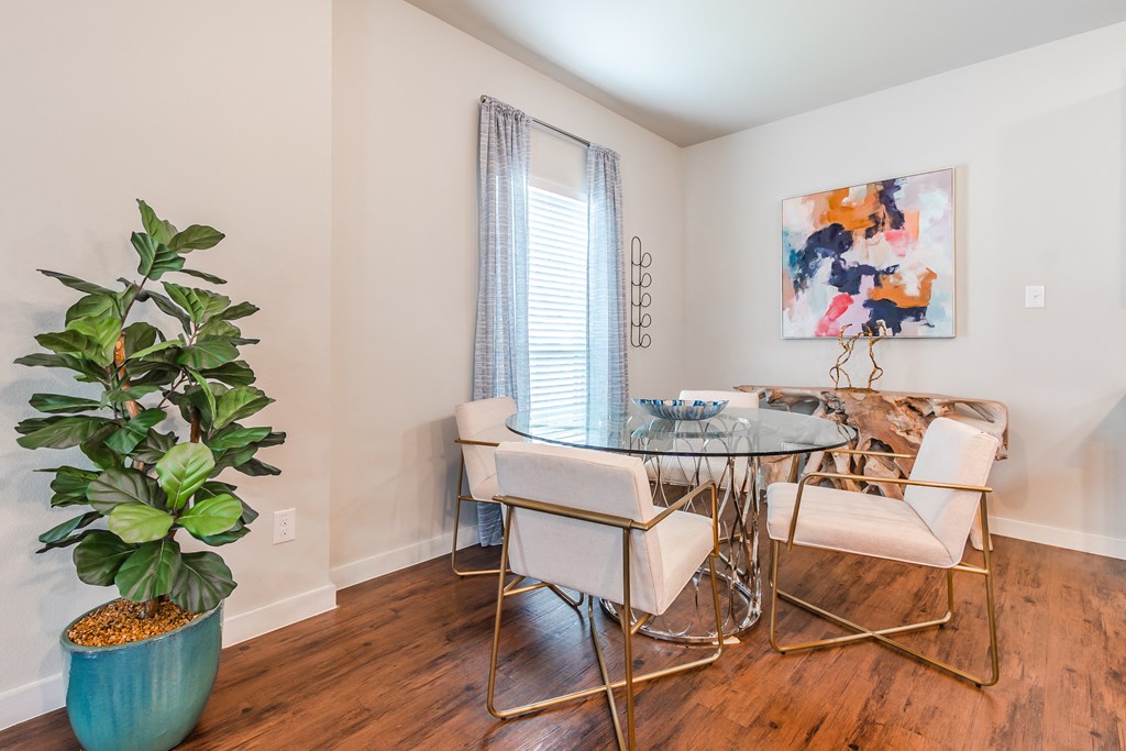 a dining room with a glass table and chairs and a potted plant