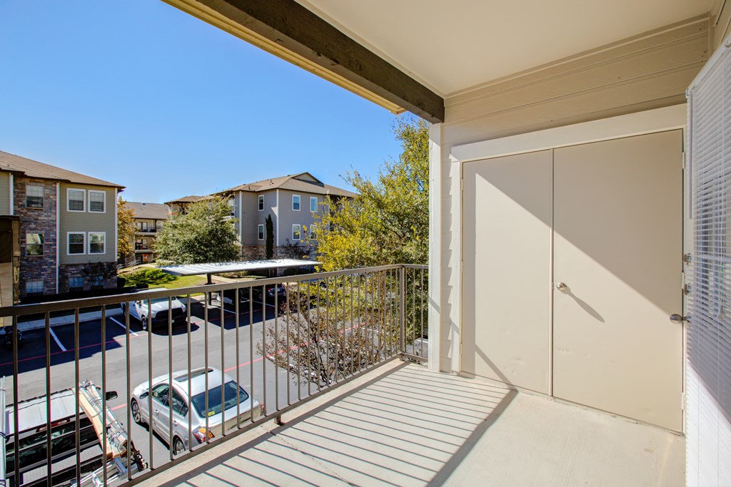 a balcony with a door and a parking lot in front of it