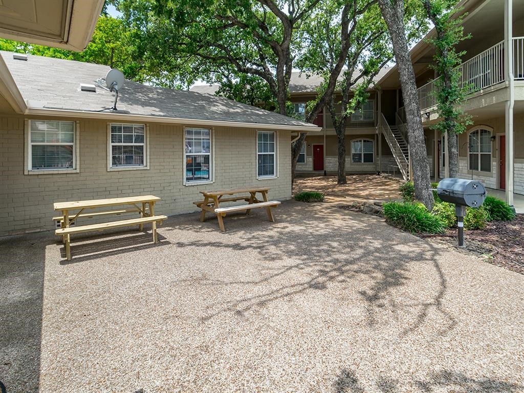 a picnic area with benches and a grill in front of a building