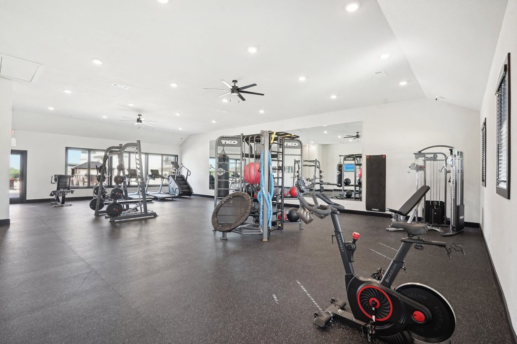 a gym with weights and cardio equipment in a building with white walls