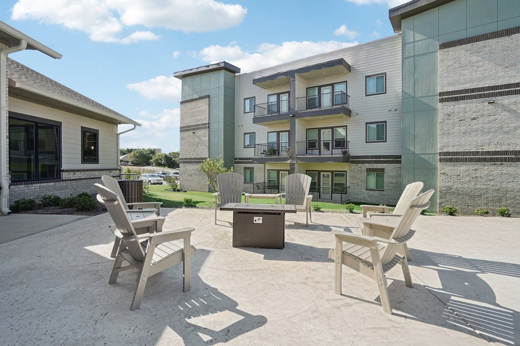 a patio with chairs and tables in front of an apartment building